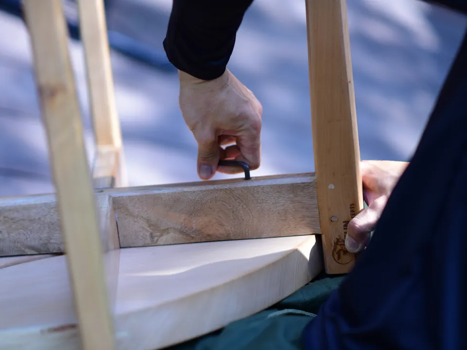 Hands dismantling or assembling wooden furniture with a hand tool