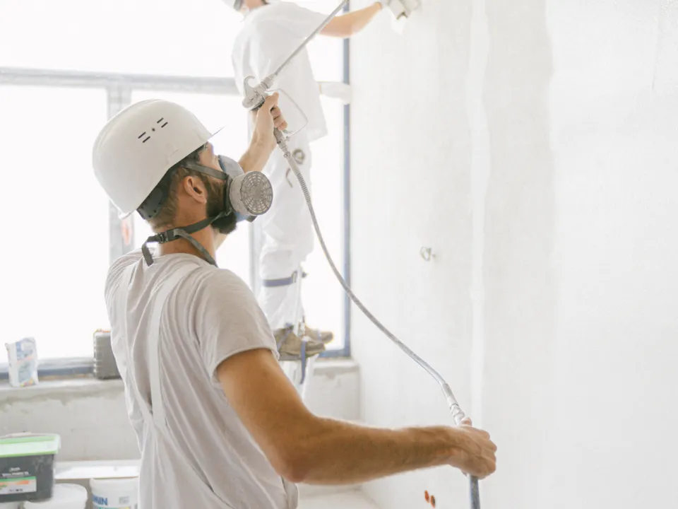 Professional painters spraying an interior wall during renovation