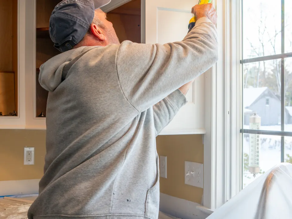 Handyman applying sealant around an interior window frame