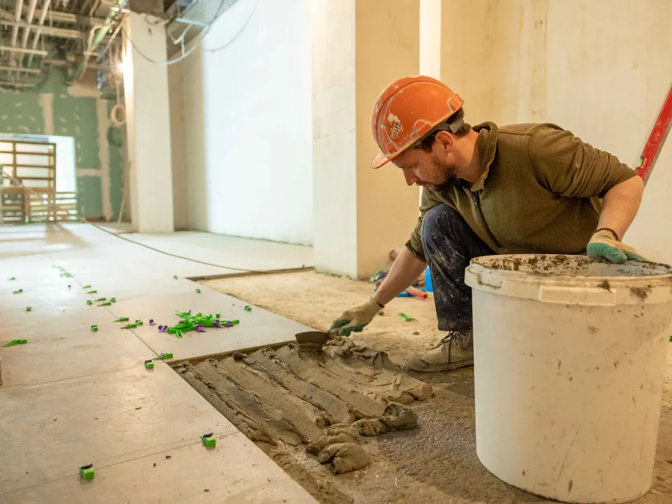 Worker laying floor tiles in an indoor renovation project