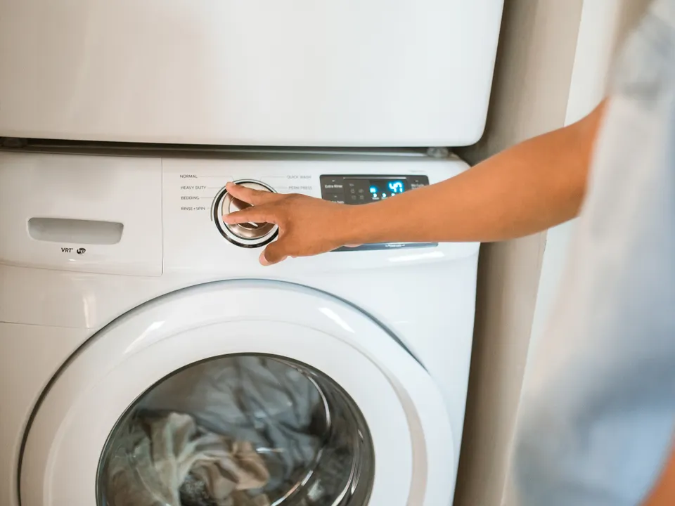 Person adjusting controls on a front-load washing machine