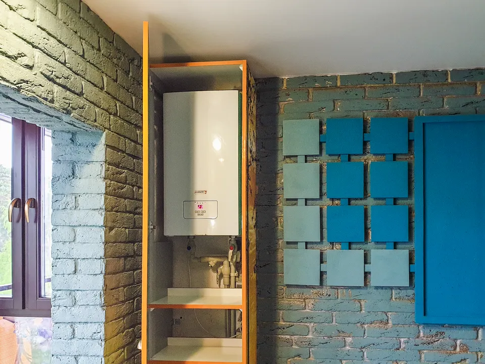 Wall-mounted water heater installed in a compact bathroom cabinet