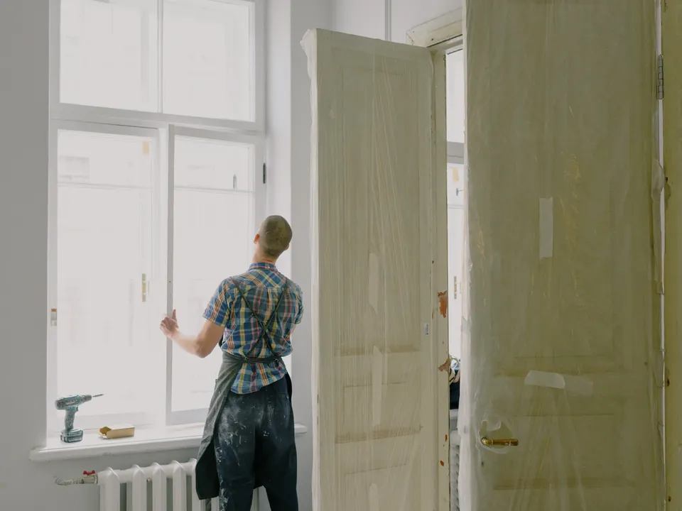 Handyman installing and adjusting a window frame inside a home